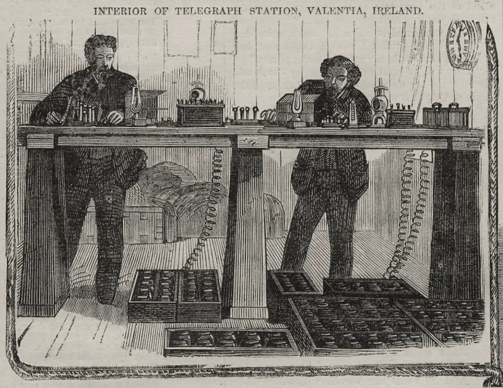 Grabado de 1865: dos telegrafistas de barba, de pie frente a una mesa larga llena de aparatos, lámparas y baterías, atienden los mensajes; bajo la mesa hay cajas con pilas eléctricas, y en la pared, un reloj.